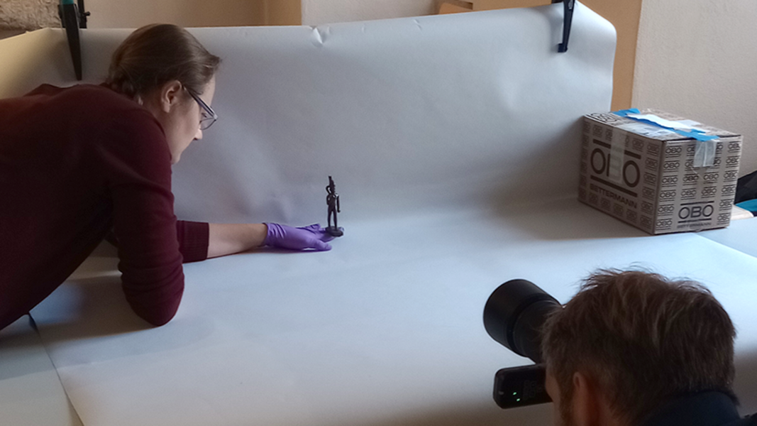 Leah Kupferschmied hält einen Uschebti der Ägyptologischen Sammlung, während Valentin Marquardt fotographiert