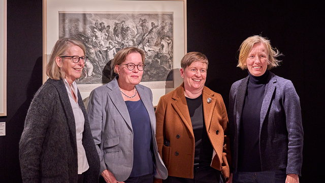 Gruppenbild von (v.l.n.r.) Prof.in Dr. Gerok-Reiter, Prof.in Anja Wolkenhauer, Dr. Ariane Koller und Prof.in Anna Pawlak vor einem gerahmten hellen Druck vor dunklem Hintergrund