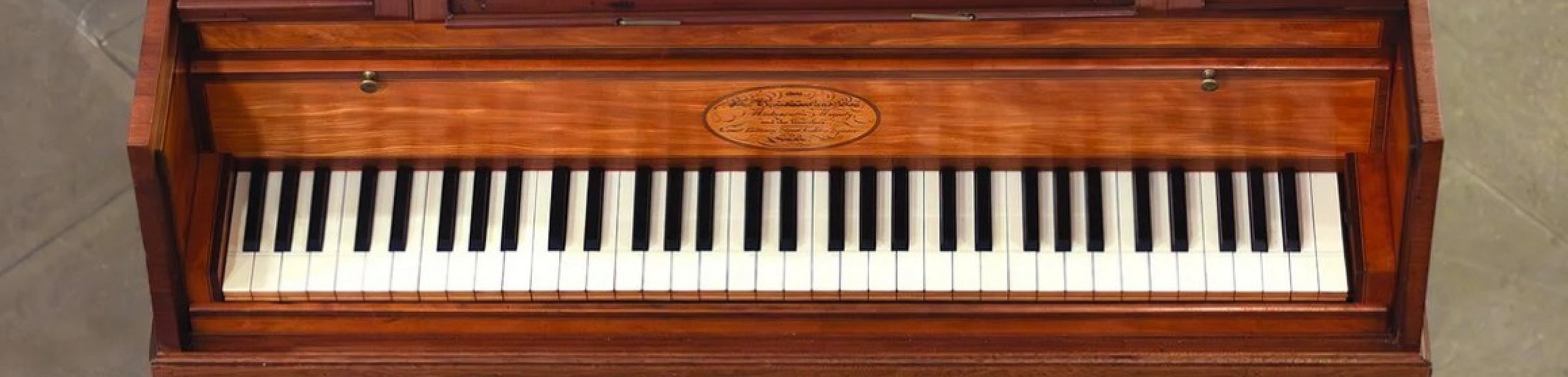 Ausstellungsplakat "The Pianoforte Age" mit dem Bild eines historischen Pianoforte oben zentral, darunter der Titel mit Untertitel "Music and Modernity  Before the Modern Piano" und darunter zwei grau hinterlegte Kästen mit Veranstaltsdaten und Öffnungszeiten