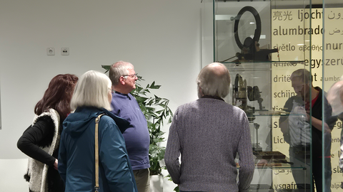 Teilnehmende der Sonderführung der Freunde des MUT stehen vor einer Glasvitrine im erleuchteten Wartebereich der Augenklinik