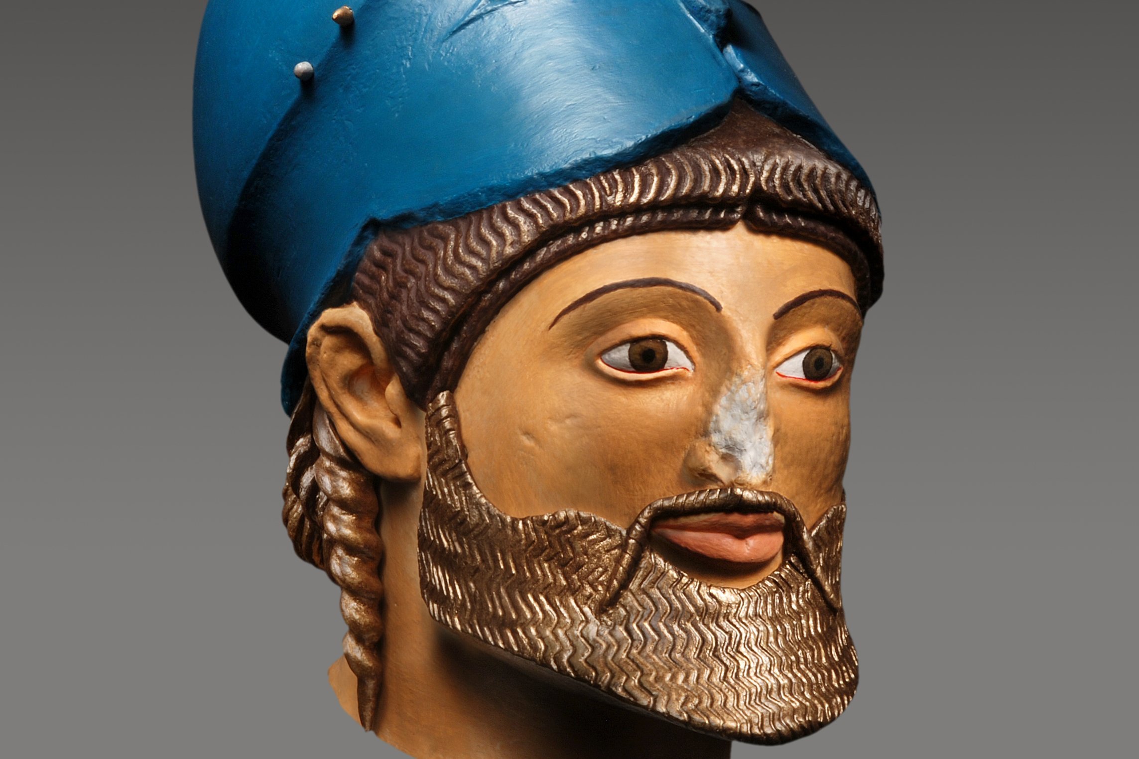 Bunt bemalter Kopf eines brünetten, bärtigen Mannes mit auf dem Hinterkopf aufgesetztem, blauem Helm