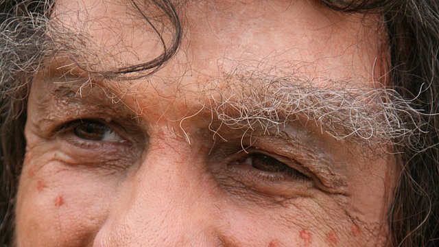 Rudolf Walter in Maske, mit aufgetragener Braue und Zahnprothese, als Neandertaler
