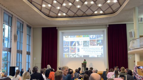 © MUT | Lucas Rau Zu sehen sind etliche Menschen, die der Eröffnungsrede zur Tagung lauschen