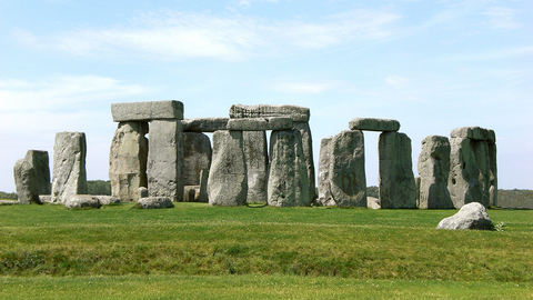 Der Stonehenge-Monolithenzirkel auf grüner Wiese unter blauem Himmel