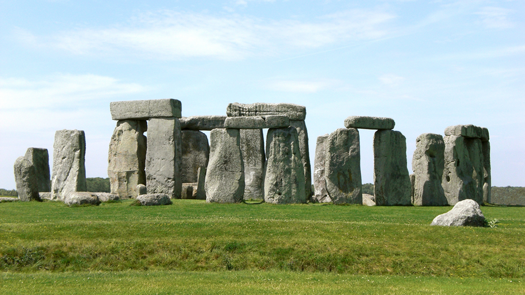 Der Stonehenge-Monolithenzirkel auf grüner Wiese unter blauem Himmel