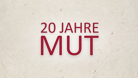 Burgunderroter Schriftzug "20 Jahre MUT" über zwei Zeilen mit weißem Leuchteffekt auf steinartigem Grund