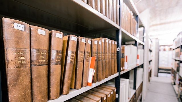 Universitätsarchiv Tübingen Archivregal mit alten, breiten Buchrücken, die bis zu einem Fluchtpunkt rechts im Bild verschwimmen