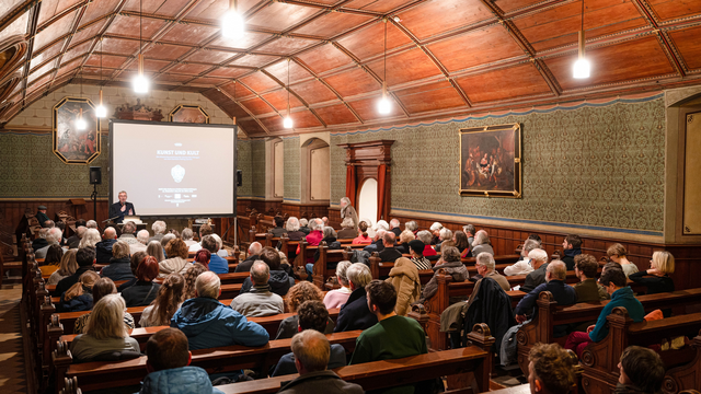 © MUT | Valentin Marquardt View of the castle church with a beamer and screen in front of the altar; at the lectern stands Prof. Dr. Ernst Seidl