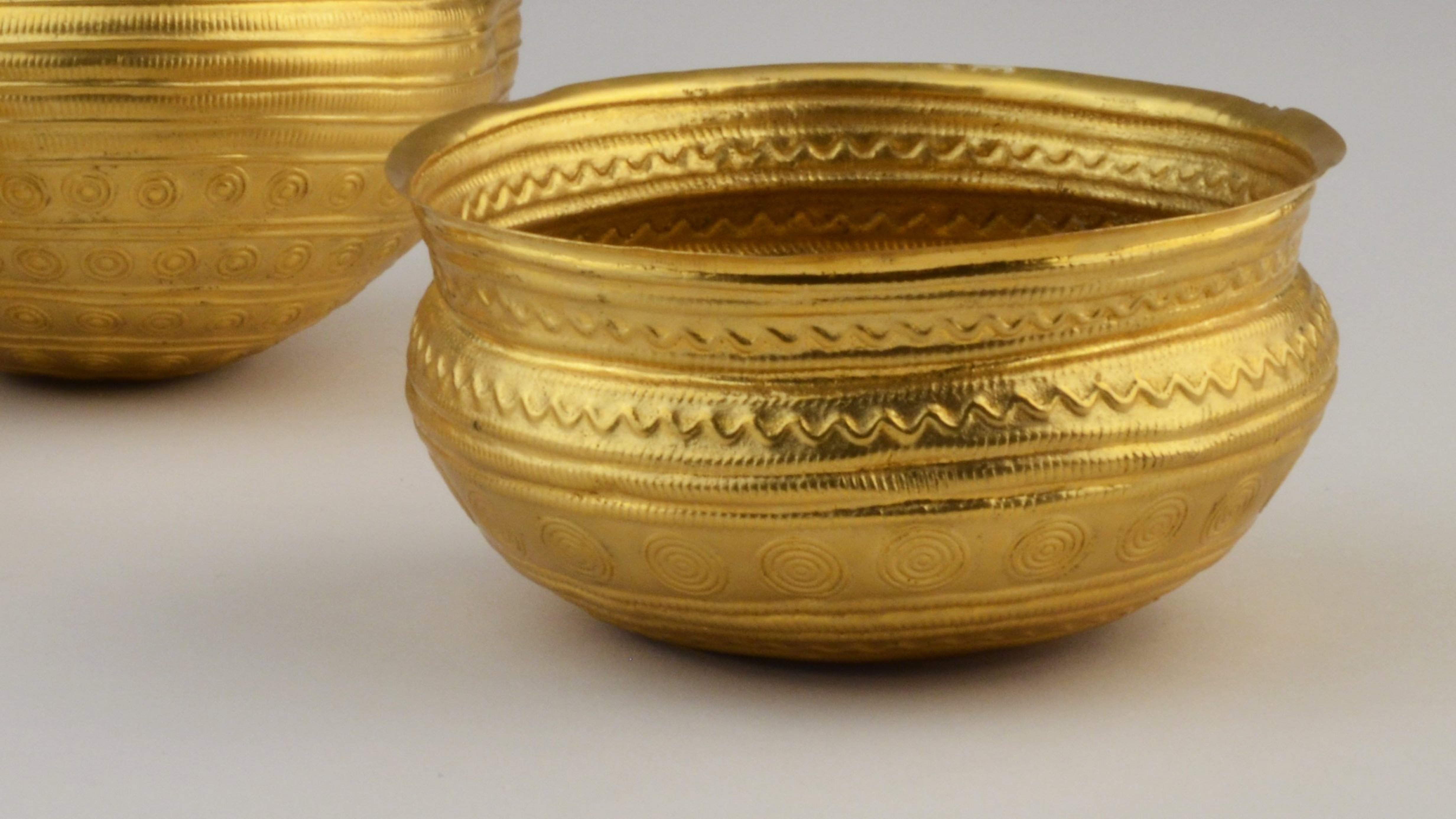 Three golden bowls with s-shaped intersection and spiral as well as wave decor