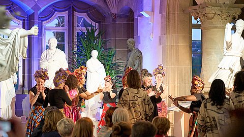 © MUT | Fabian Kurze Tanzende Darstellerinnen in farbenfrohen Kleider im Rittersaal von Schloss Hohentübingen bei der Modenschau.