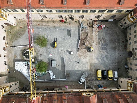 © Hermann Paule GmbH & Co. KG | H. Singer Zu sehen ist eine Luftansicht vom Schlosshof mit Material zum Ausbau der Fernwärmeleitung