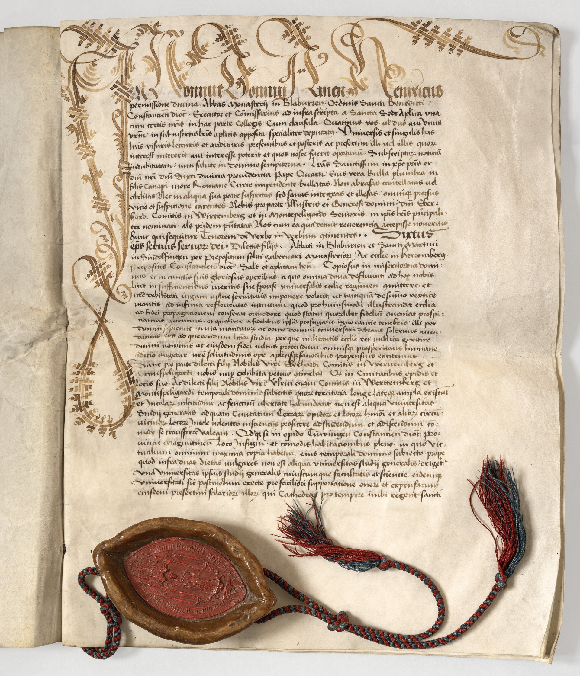 Abbildung einer historischen Urkunde auf Pergament mit kunstvoll gestalteten Initialen und einem großen roten Wachssiegel, das an einem langen, gedrehten Band befestigt ist. Der Text ist in einer kalligrafischen Schrift verfasst. Am oberen Rand hängen dekorative Schnüre herab.