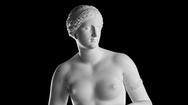 Photo: MUT | Valentin Marquardt Bust detail of a photograph of a white moulding, depicting an naked Aphrodite with her head tilting to the right; she is wearing an armband on her left biceps
