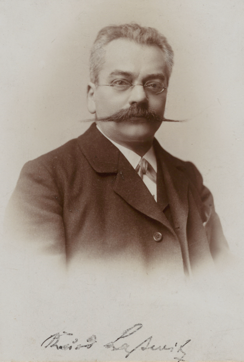 Sepiafarbenes Portrait eines Mannes mit kurzen Haaren, rundlichem Gesicht und breitem Schnauzbart. Darunter der Name "Kurd Laßwitz" in Kurrentschrift