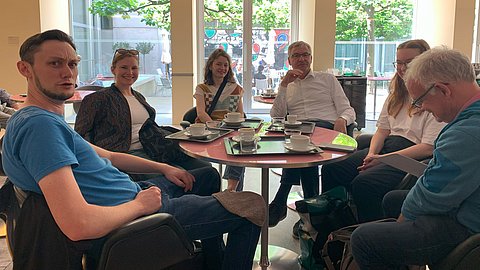 © MUT | Simon Zauner Auf dem Bild sind von links nach rechts einige der Mitarbeiterinnen und Mitarbeiter des MUTs an einem Café-Tisch zu sehen: Fabian Kurze, Annika Vosseler, Diellëza Hyseni, Ernst Seidl, Nele Morath und Edgar Bierende