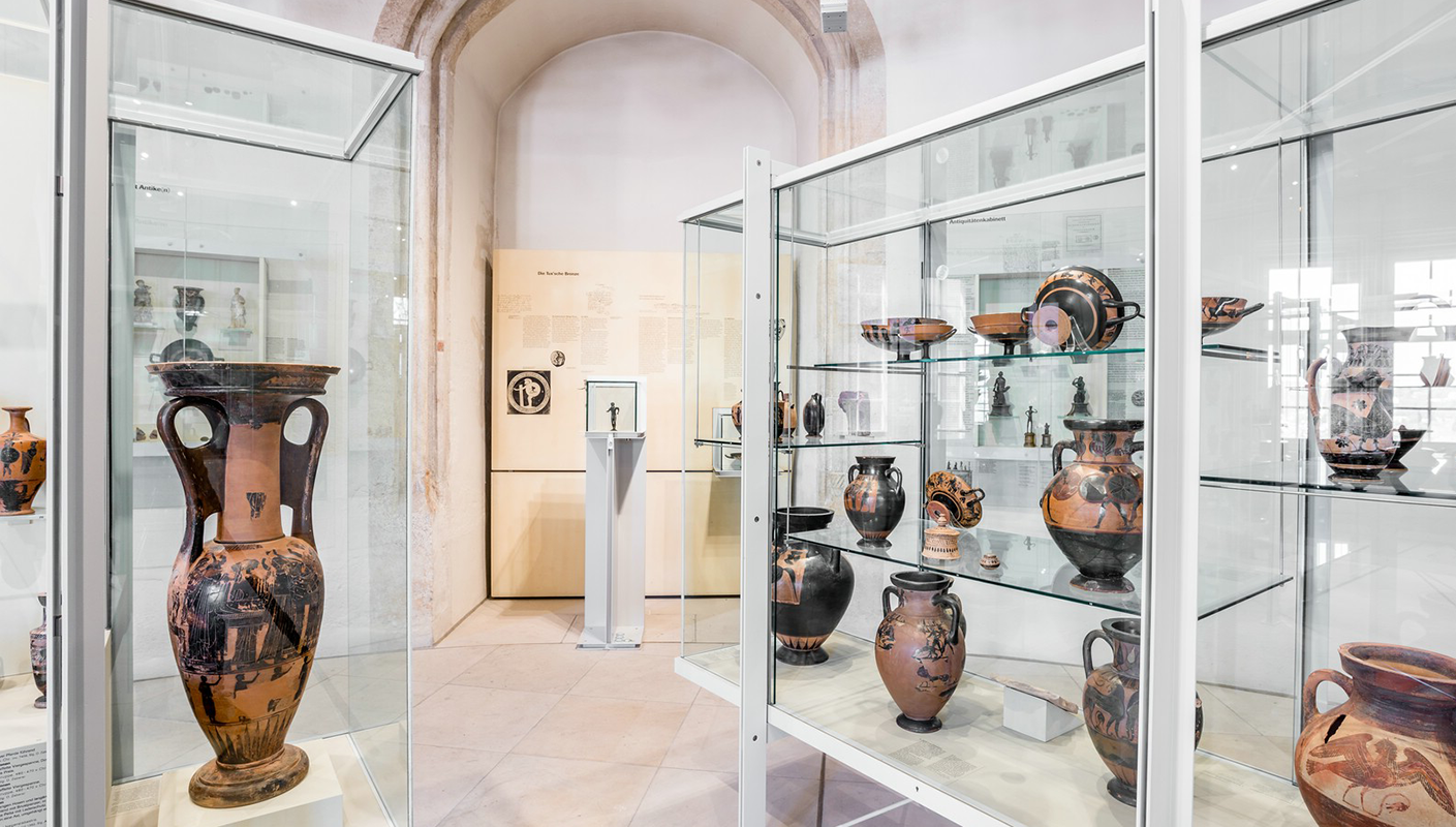 Vitrinen mit griechischer Keramik im Rundturm im Museum Alte Kulturen und im Hintergrund der Waffenläufer in einer drehbaren Vitrine
