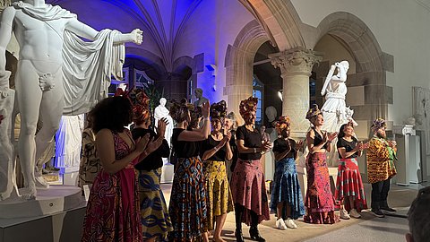 © MUT | Lucas Rau Tanzende Darstellerinnen in farbenfrohen Kleider im Rittersaal von Schloss Hohentübingen bei der Modenschau.