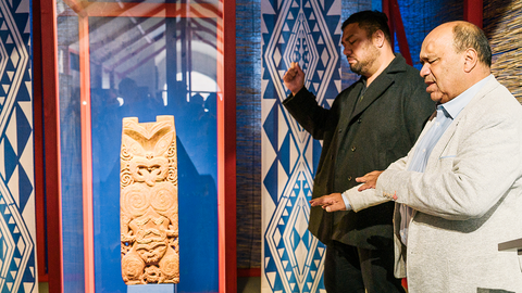 Victor Walker und Shanan Grey in andächtigen Gesten rechts vor der beleuchteten Vitrine mit Hinematioros Pou (links)