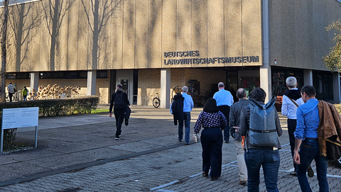 Teilnehmende des Sammlungstags BW laufen nach links hinten ins Bild auf ein Gebäude der Universität Hohenheim zu, das von der Sonne beschienen wird