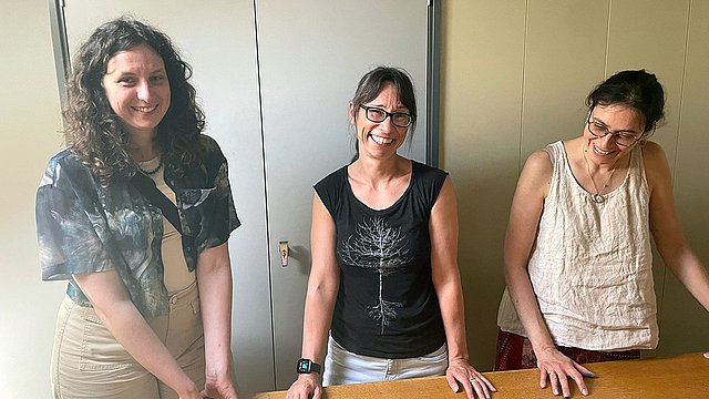 Dr Anne Kremmer (links), Sarah Fründt (mittig) und Karina Gerdau (rechts) vor einem Arbeitstisch