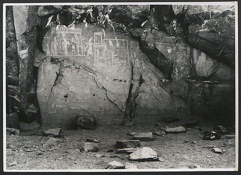 Schwarz-Weiß-Fotografie eines Höhlenraums mit an der hinteren Felswand angebrachtem Bild im ägyptischen Stil