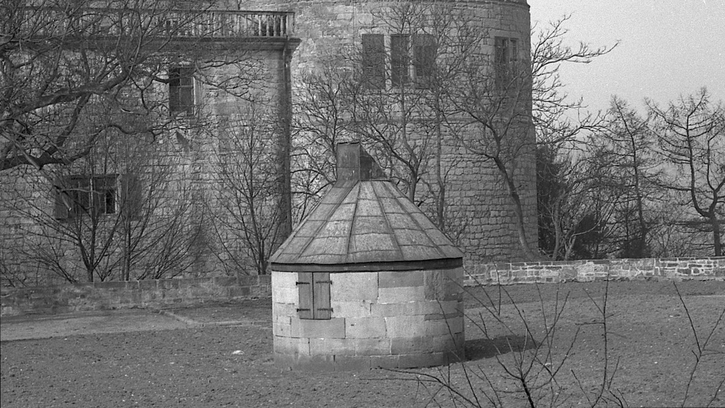 Schwarz-Weiß-Foto der Ostbastion von Schloss Hohentübingen mit dem Nordostturm im Hintergrund und der runden, unscheinbaren Sternwarte auf dem Rasen im Vordergrund