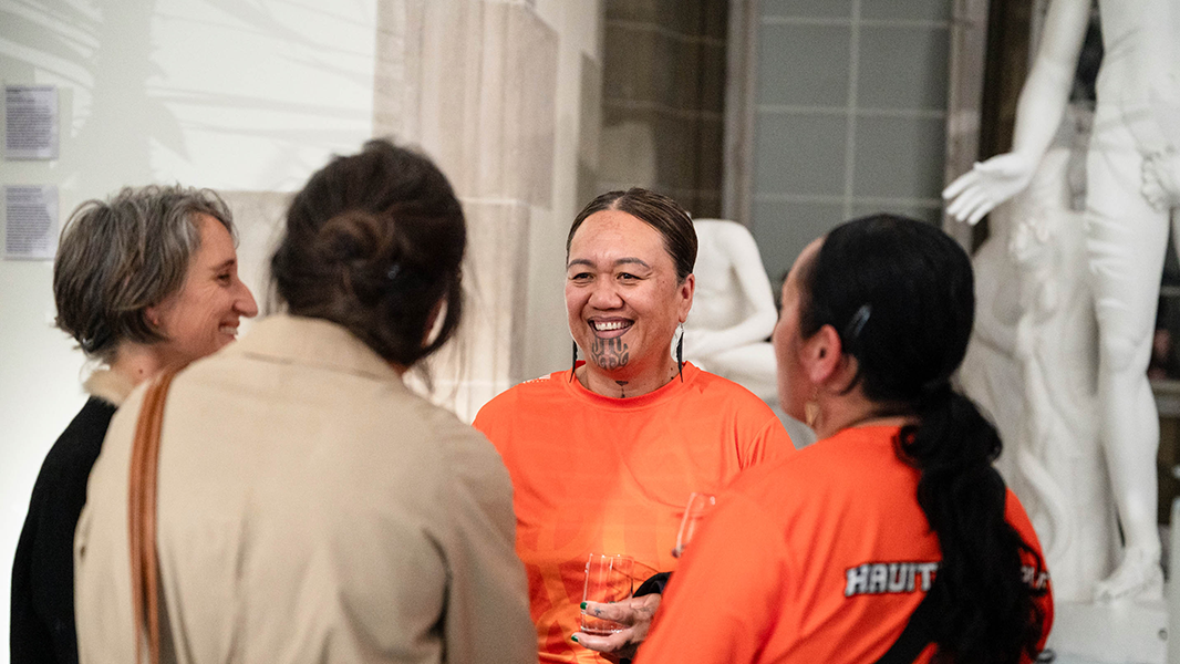 Im Rittersaal tauscht sich Chantal Arold vom Ethnologischen Institut mit zwei Vertreterinnen der Te Aitanga-a-Hauiti aus, erkennbar an dem gleichen orangenen Shirt