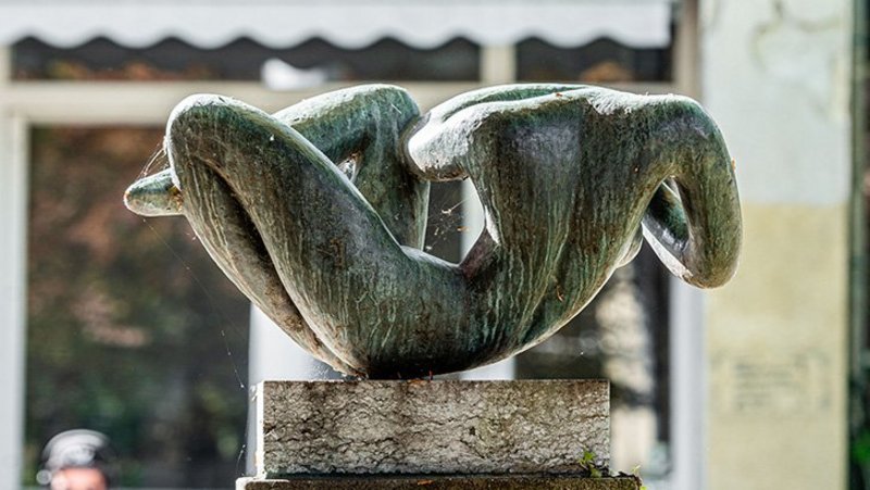 Liegender weiblicher Akt mit hinter dem Kopf verschränkten Armen in Bronze, die nur mit dem Beckenbereich die Plinthe berührt