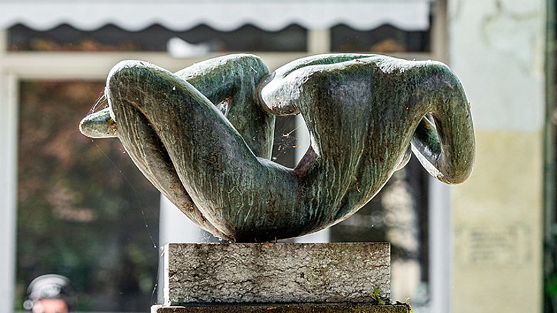 Liegender weiblicher Akt mit hinter dem Kopf verschränkten Armen in Bronze, die nur mit dem Beckenbereich die Plinthe berührt