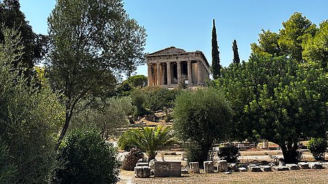 Blick auf die Ostfront des Hephaisteions auf der Athener Agora in der hinteren Bildmitte, umrahmt von Zypressen im Vordergrund