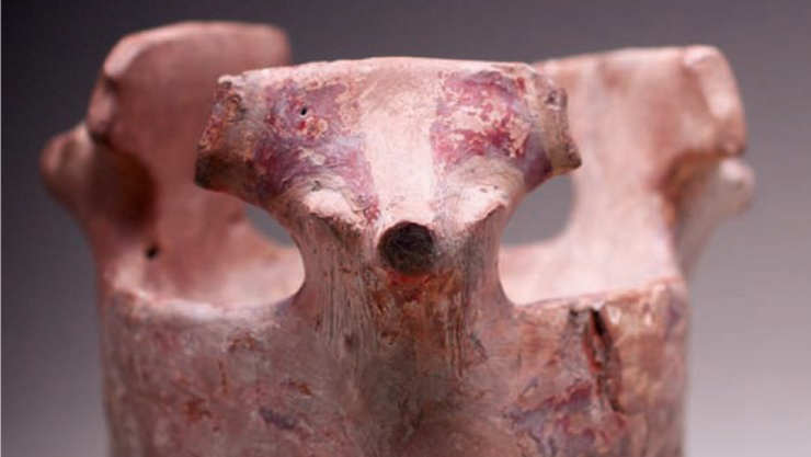 [Translate to Englisch:] Gefäß auf drei Beinen mit stilisierten Tierköpfen, rötlich-braun mit Spuren von Bemalung