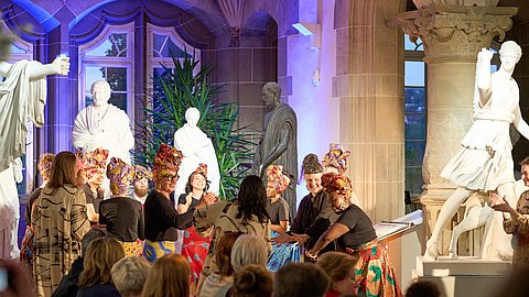 © MUT | Fabian Kurze Tanzende Darstellerinnen in farbenfrohen Kleider im Rittersaal von Schloss Hohentübingen bei der Modenschau.