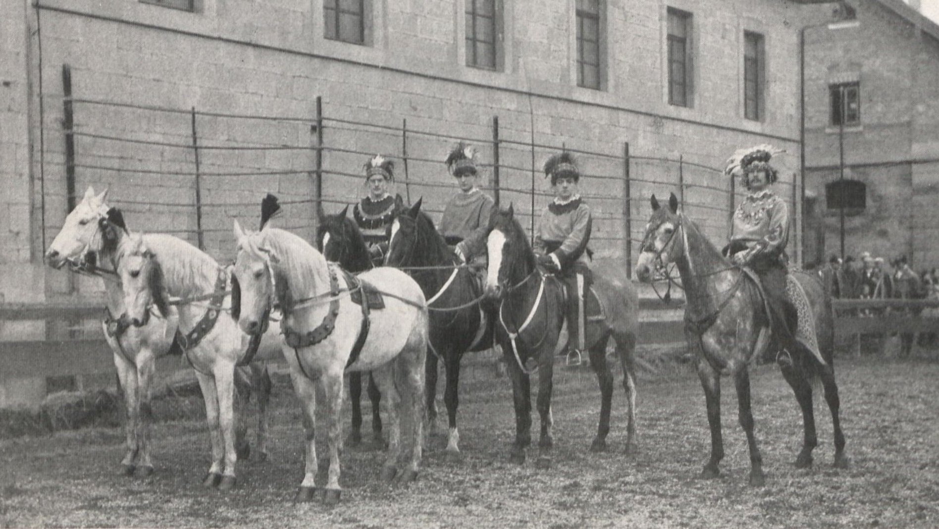Schwarz-weiß-Foto einer Gruppe kostümierter Studierender auf Pferden mit herausgeputzten Handpferden