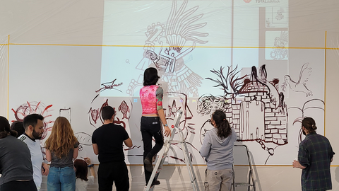 Foto: MUT | Ernst Seidl Studierende der Spring School 2025, teils auf einer Trittleiter, die eine Projektion südamerikanischer Kunst auf einer Wand abzeichnen