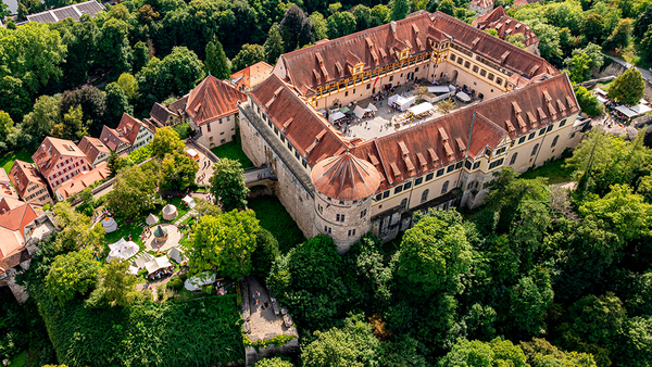 Vogelperspektive auf Schloss Hohentübingen mit sichtbaren Zeltaufbauten im Innenhof und auf der Ostbastion links im Bild, darum herum Begrünung