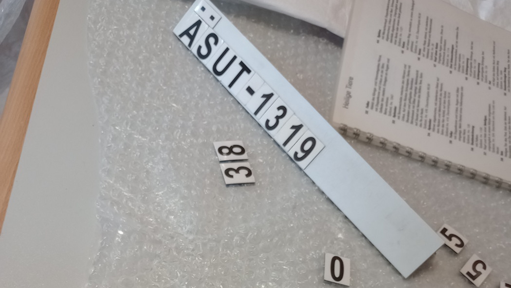 Magnetische Tafel mit magnetischen Buchstaben, die eine Inventarnummer "ÄSUT-1319" bilden auf Luftpolsterfolie