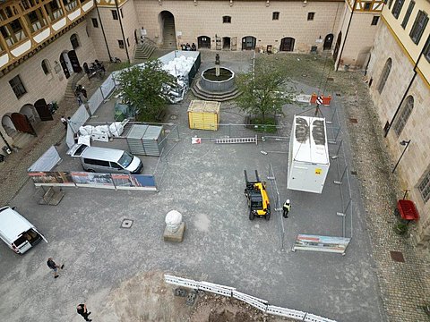 © Hermann Paule GmbH & Co. KG | H. Singer Zu sehen ist eine Luftansicht vom Schlosshof mit Material zum Ausbau der Fernwärmeleitung