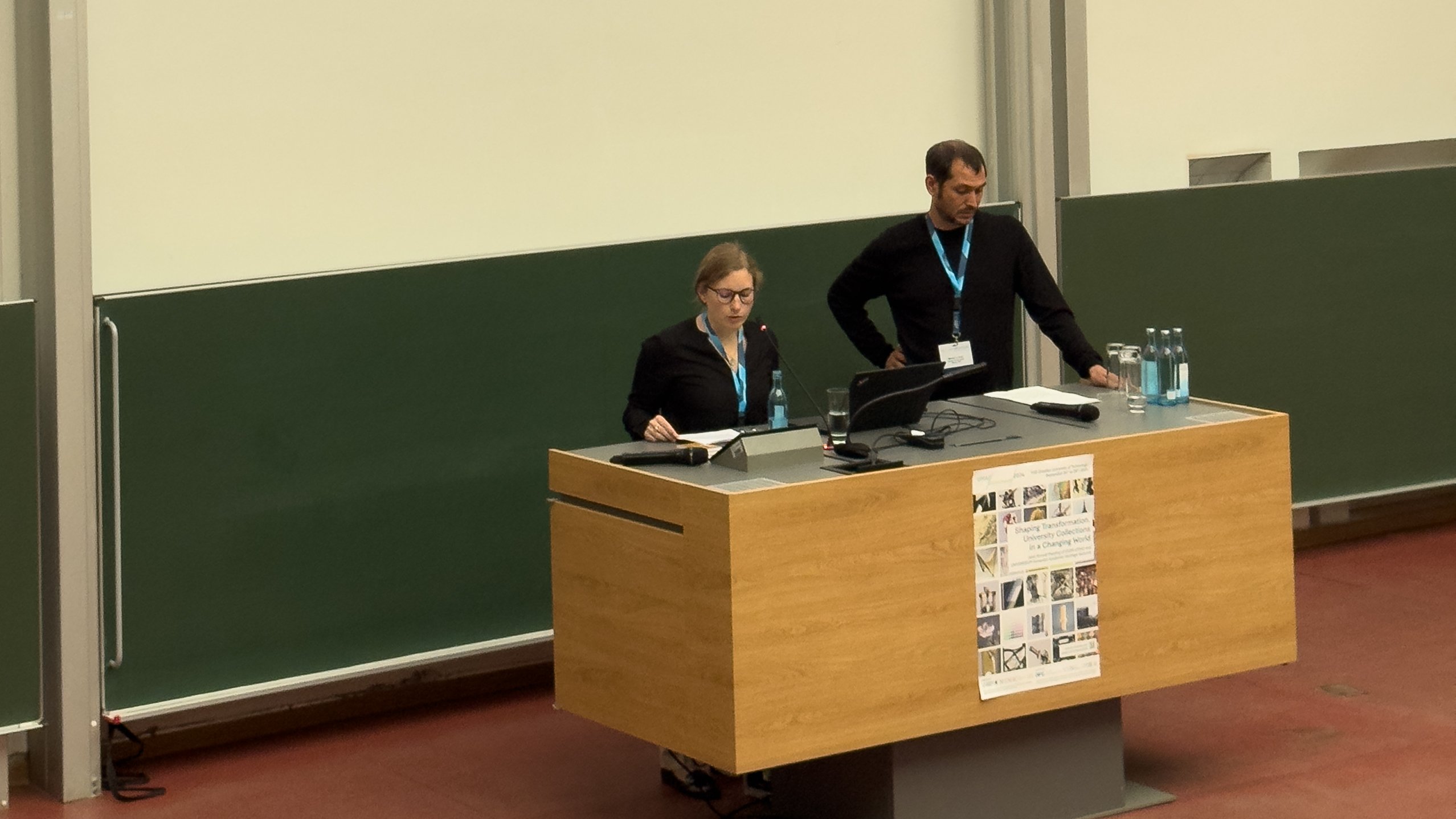 Zu sehen sind zwei Mitarbeitende des MUTs beim Halten einer Präsentation an einem Rednerpult