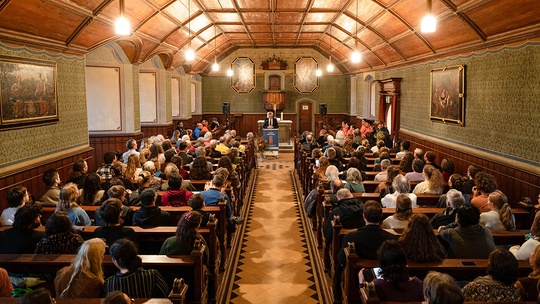 Blick durch die vollbesetzten Kirchenbänke der Schlosskirche von Schloss Hohentübingen hindurch bis zu einem aufgebauten Rednerpult, an dem Museumsdirektor Professor Dr. Ernst Seidl steht
