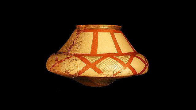 Conical ceramic vessel painted with bridght red stripe decor, against black background
