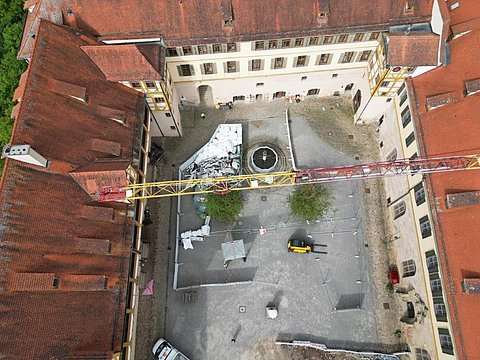 © Hermann Paule GmbH & Co. KG | H. Singer Zu sehen ist eine Luftansicht vom Schlosshof mit Material zum Ausbau der Fernwärmeleitung
