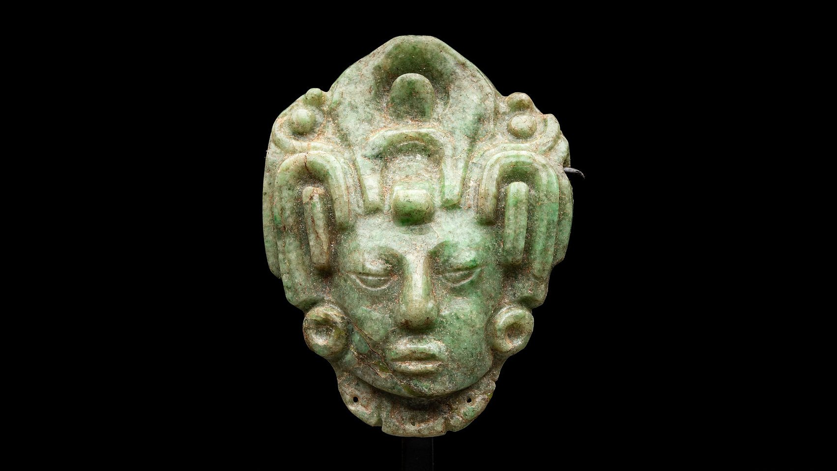 Central green jade maize god head against black background