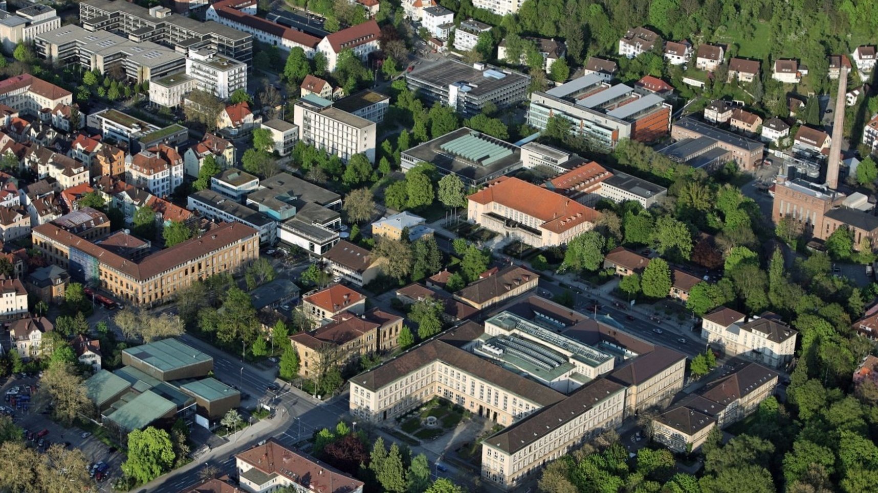Luftaufnahme der Universitätsgebäude um die Wilhelmstraße, Tübingen, mit der prominenten u-förmigen Anlage der Neuen Aula unten rechts im Bild, dem Bonatzbau schräg darüber zu sehen und Hegel- und Brechtbau gen links oben fortlaufend.