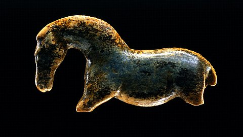 Foto: Juri Lipták Nach links gewandte Wildpferdfigurine aus Elfenbeinmarmor mit gewölbtem Hals vor schwarzem Hintergrund