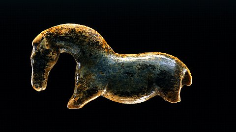 Nach links gewandte Wildpferdfigurine aus Elfenbeinmarmor mit gewölbtem Hals vor schwarzem Hintergrund