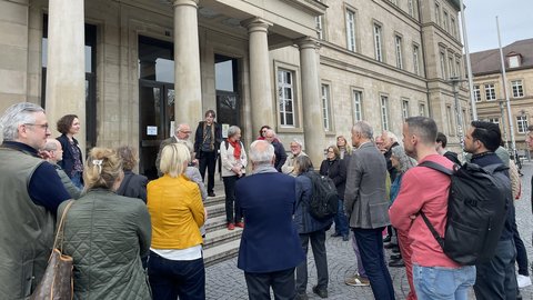 Foto: Universität Tübingen Dr. Edgar Bierende spricht vor einer Gruppe aus Alumni der Universität Tübingen vor dem Hintergrund des Porticus der Neuen Aula in der Wilhelmstraße