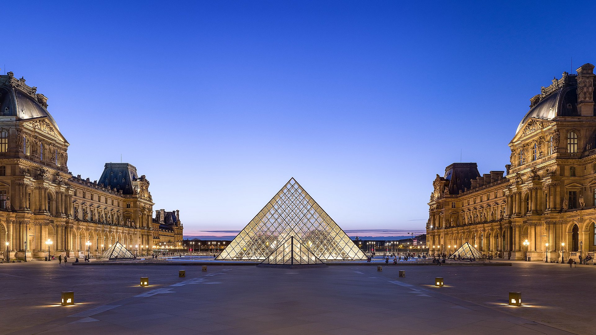 Blick nach Westen auf den Napoleonhof des Louvre mit Pyramide in der Abenddämmerung