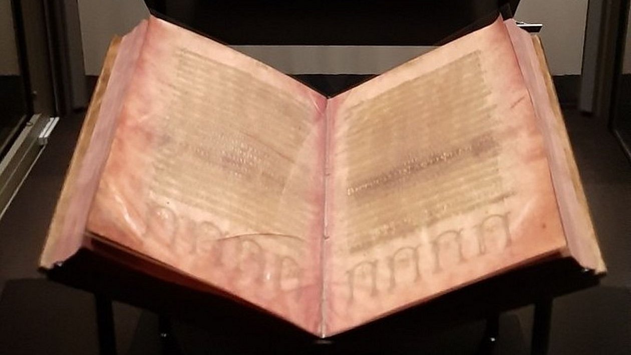 Foto: Universitätsbibliothek Tübingen In einer Vitrine aufgeschlagenes Buch auf schwarzem Grund; die Seiten des Codex Argenteus sind mit Silberfarbe beschrieben