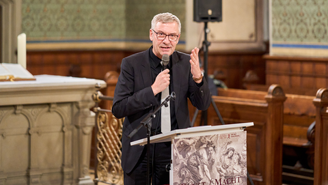 Museumsdirektor Prof. Dr. Ernst Seidl spricht am Rednerpult mit dem Plakat der Ausstellung "Kunst / Macht" mit gestikulierend erhobener Hand ins Mikrophon