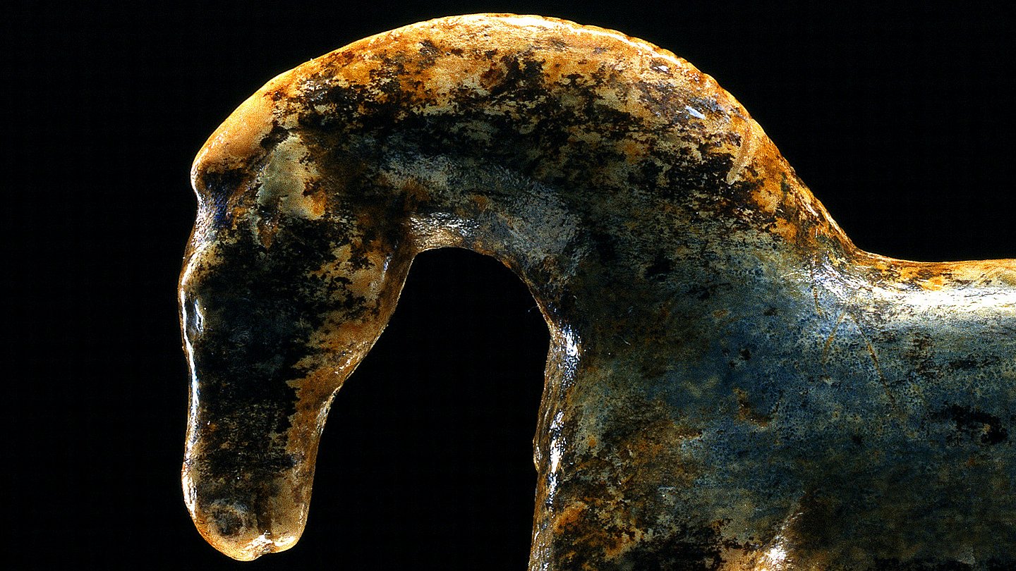 Foto: MUT | Juraj Liptak Nach links gewandte Pferdchenfigur aus nachgedunkeltem Mammutelfenbein; der Hals ist gewölbt, von den Beinen sind lediglich Ansätze erhalten